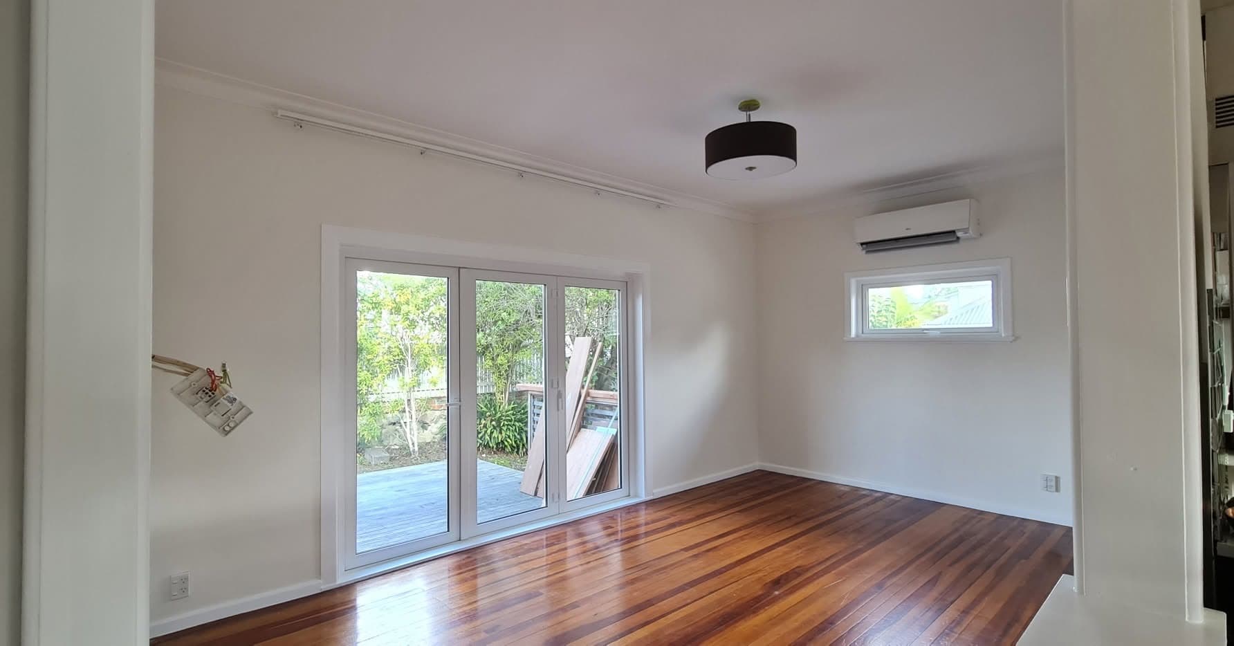 Freshly plastered and painted living room with white walls and polished wooden floors in an Auckland home